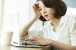 パソコンの画面を見ながら憂鬱そうな女性